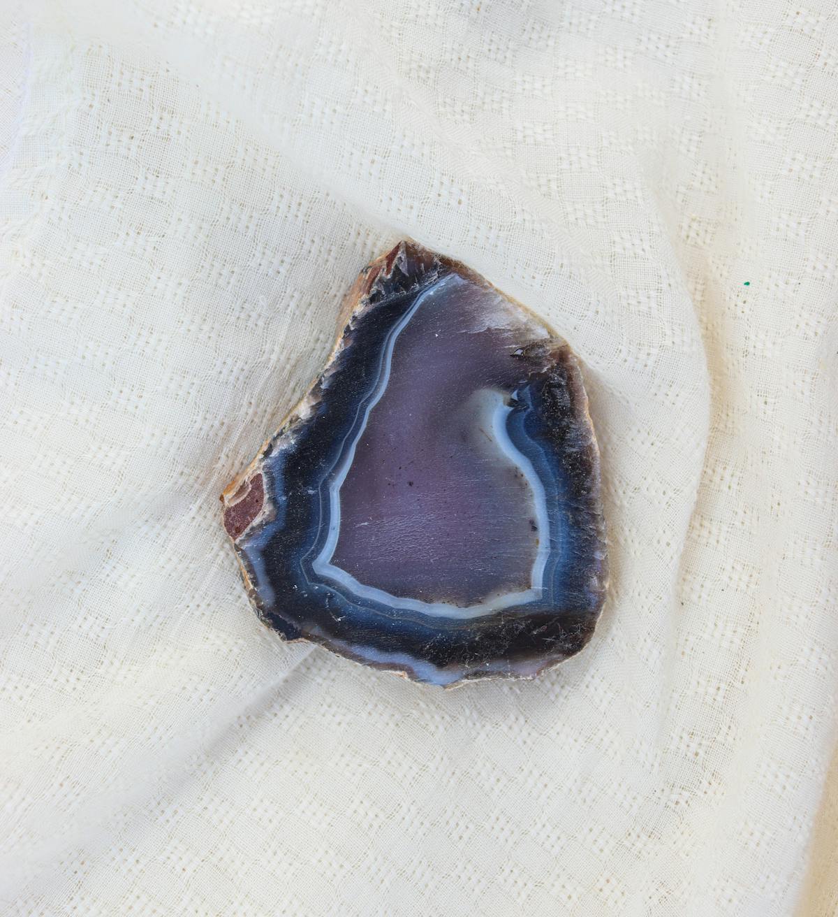 Tranche de géode d'agate avec bandes concentriques sur tissu blanc - vertus agate lithothérapie