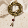 Mala Tibétain 108 Perles Bois de Verawood 10 mm — photographie produit sur travertin beige