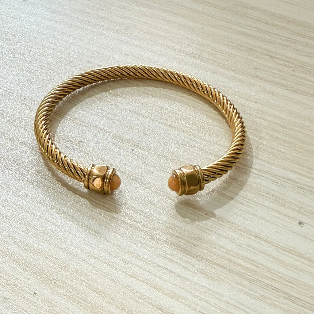 Bracelet jonc torsadé doré porté au poignet, anneau ouvert ajustable