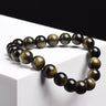 Bracelet obsidienne dorée perles 8 mm posé sur un cube blanc