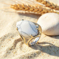 Bague Howlite réglable en métal argenté, cabochon marquise, posée sur le sable
