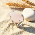 Bague Quartz Rose réglable en métal argenté, cabochon marquise, posée sur le sable